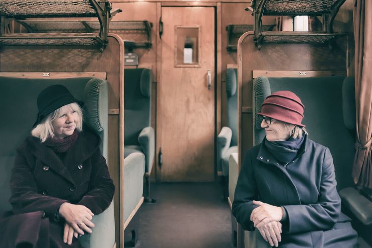Smiling women looking at each other while sitting in train