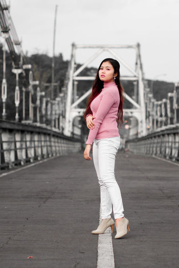 Portrait of woman standing on bridge in city