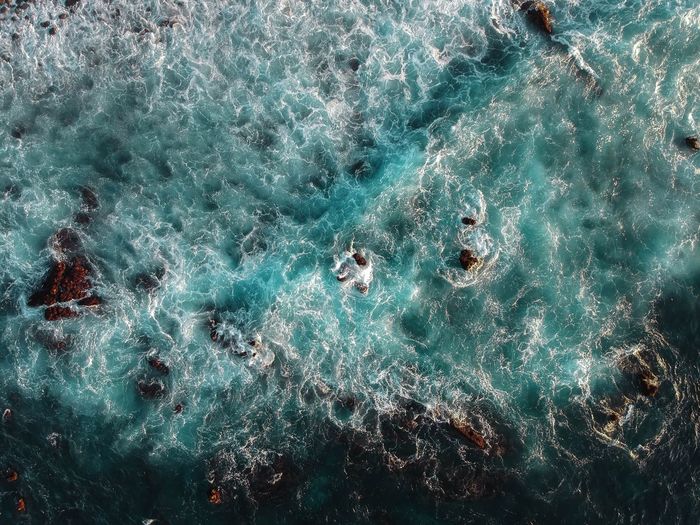 High angle view of waves by a rocky shore 