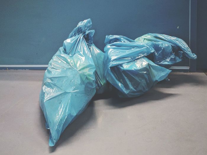 High angle view of blue garbage bags on floor by wall