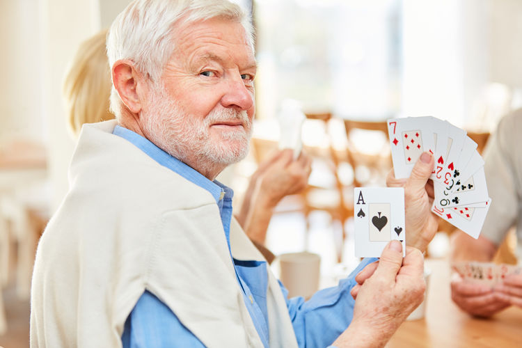 Portrait of man showing cards in nursing home