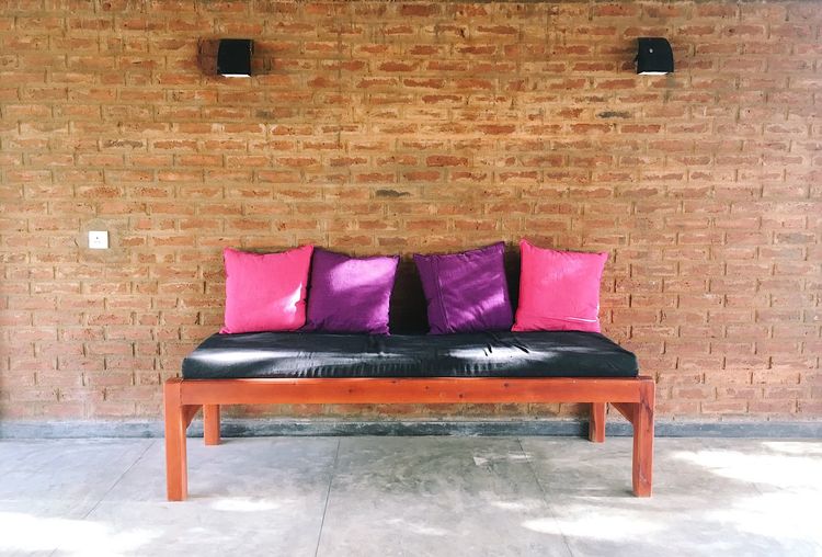 Chairs against pink brick wall
