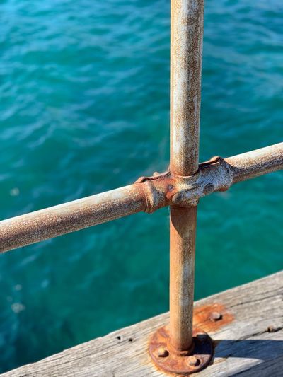 Close-up of rusty metal railing against sea