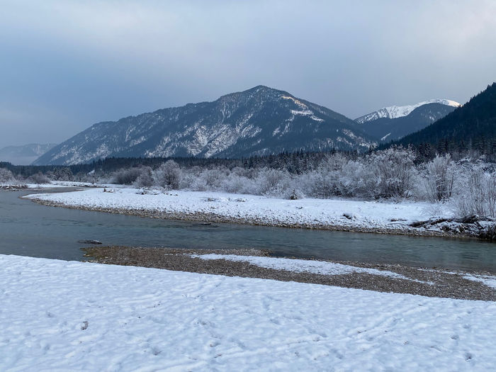 Scenic view of snowcapped tyrolean and bavarian mountains against sky in winter seen from isar river