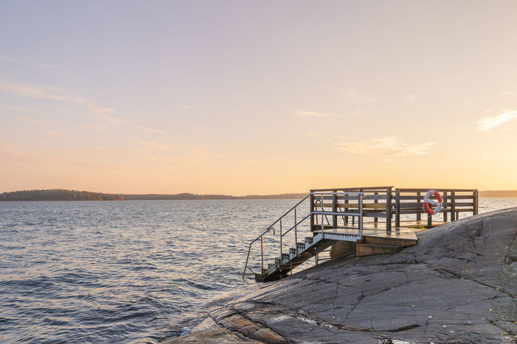 Viewing deck with stairs to baltic sea in stockholm stunning sunrise with rocks in beautiful light