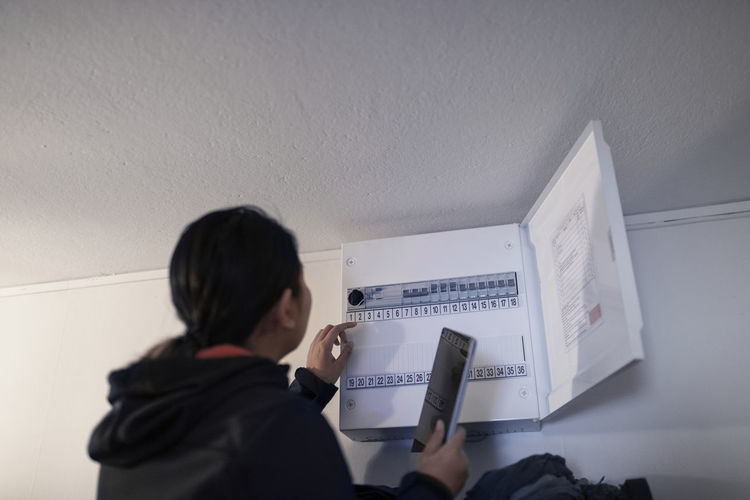 Woman checking electric fuse box