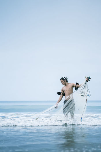 Mid adult man holding fishing net in sea