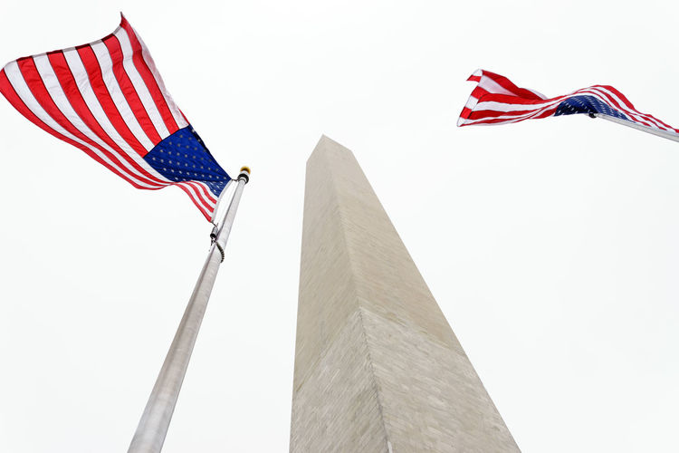 Low angle view of american flags by washington monument against clear sky
