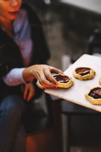Woman taking rustic plum tart from serving tray