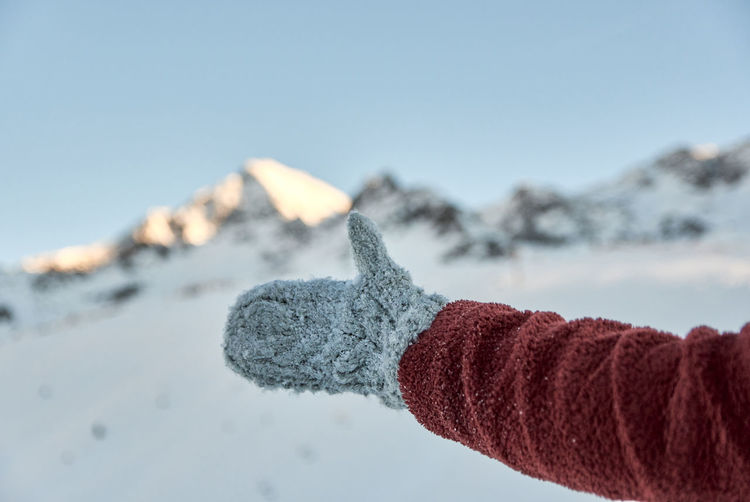 Closeup photo of a thumbs up in mittens.