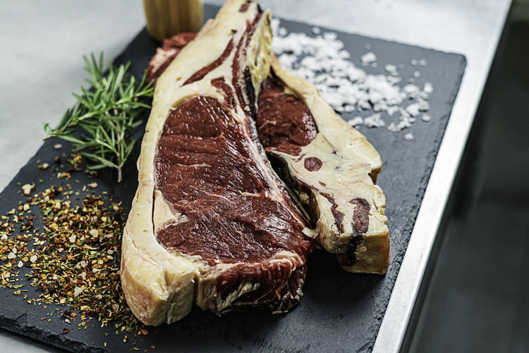 Raw steak, rosemary and salt on a serving board