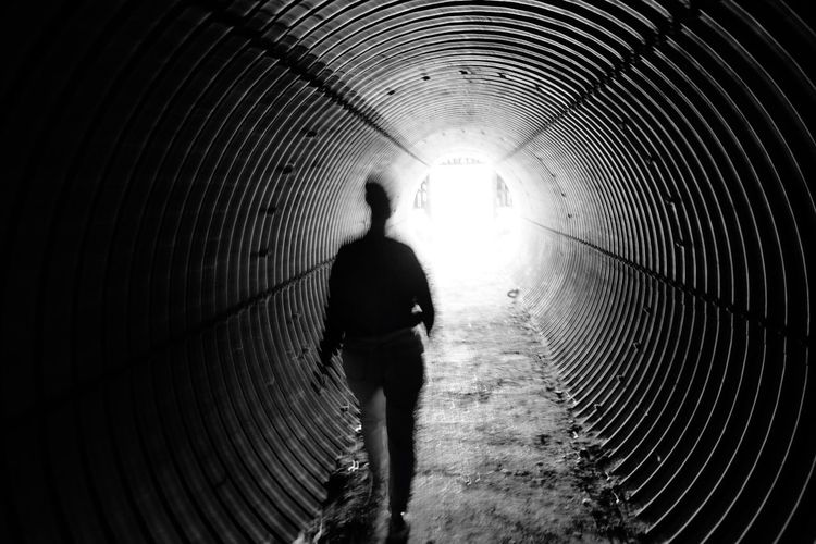Blurred motion of silhouette person walking in tunnel