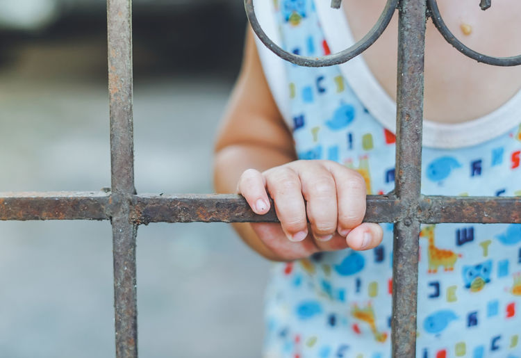 Midsection of child holding metallic window