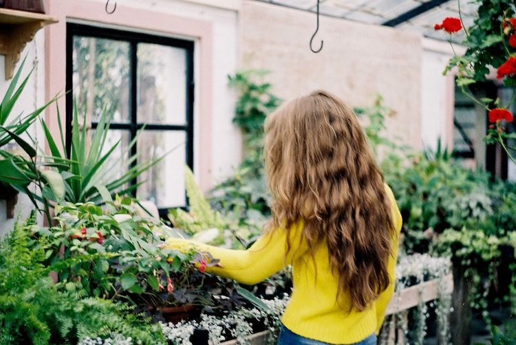 Rear view of girl standing against plants