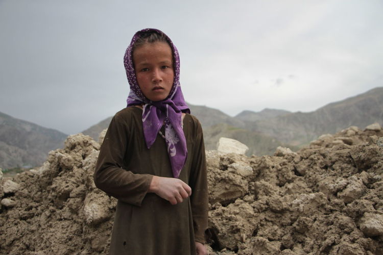 Portrait of girl wearing scarf standing against heap