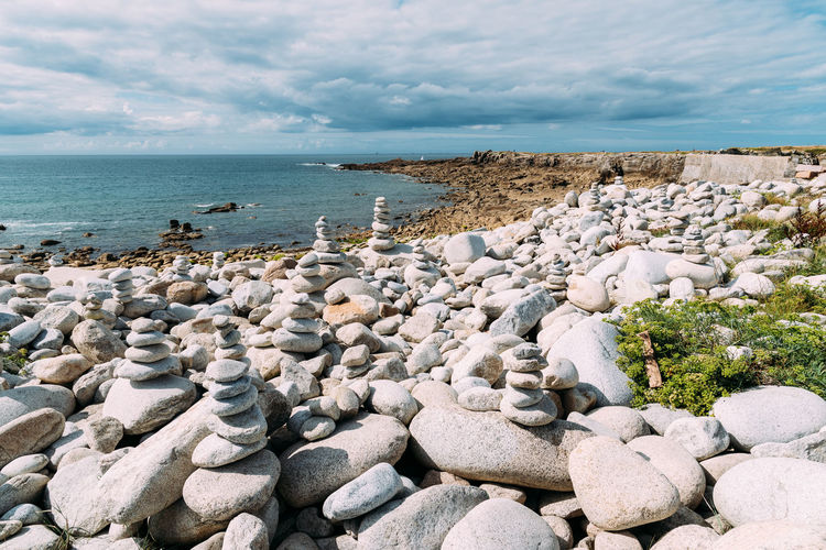 Stack of stones by sea shore against sky