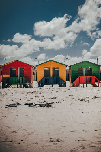 Beach huts by buildings against sky on sunny day