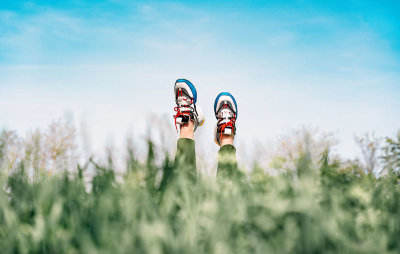 Person lying in tall grass. legs with sneakers pointed at sky