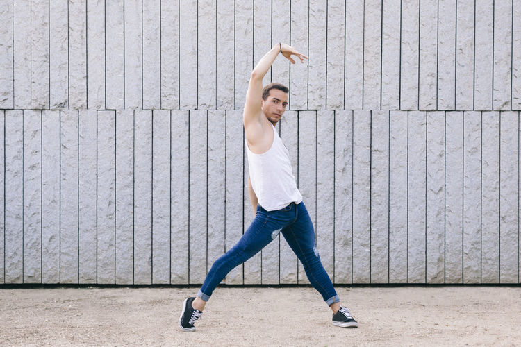 Portrait of young man dancing against wall