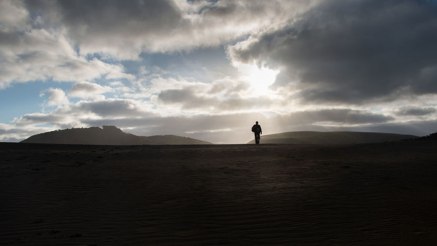 Silhouette man standing on land against sky during sunset