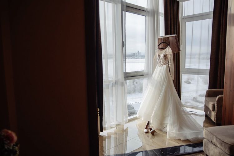 Wedding dress with shoes against windows