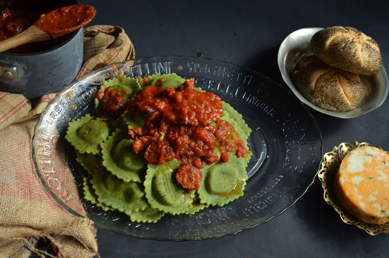 High angle view of spinach ravioli with red marinara sauce in plate on table