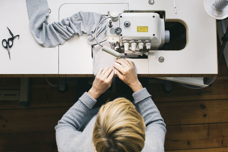 Cropped hand of man using sewing machine