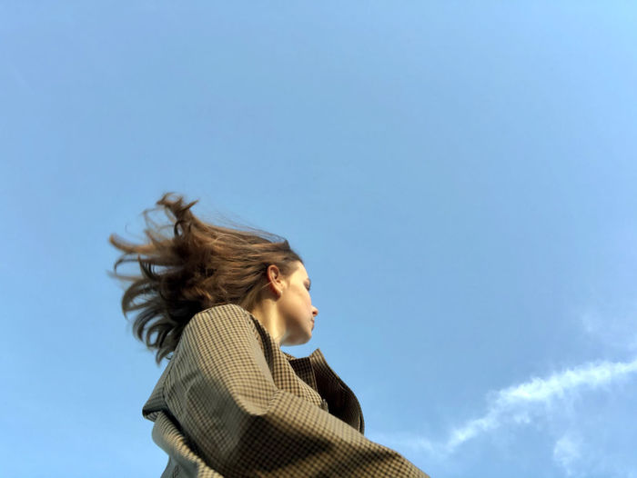 Portrait of young woman against blue sky