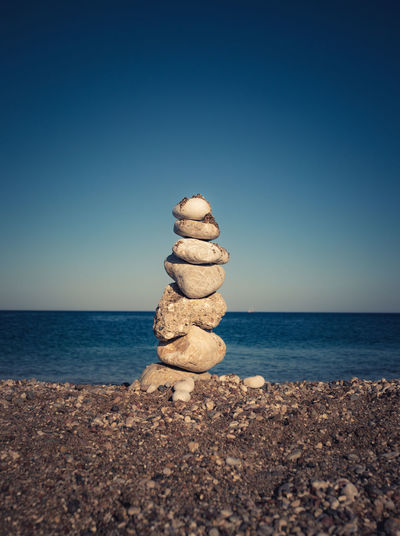 Stack of stones on beach against clear sky