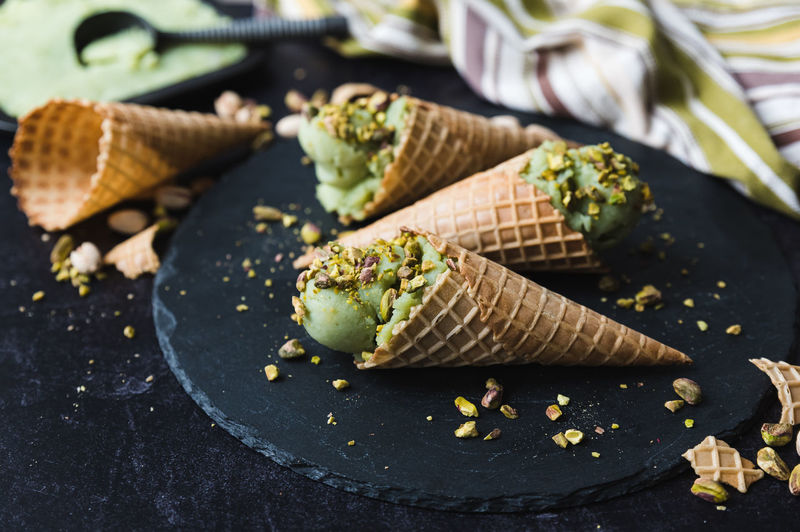 Close up of pistachio ice cream in cones on black background.