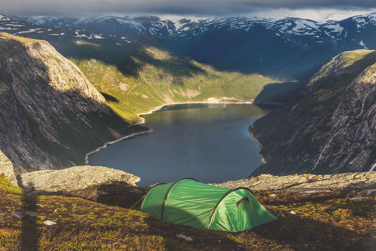 Tourist's tent in the mountains near  troll tongue rock. trolltunga. sunrise above fjord, norway.