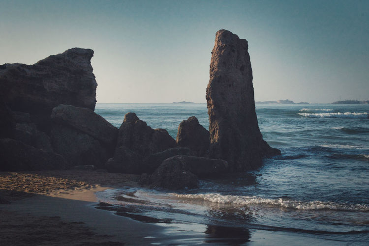 Rocks on beach against clear sky
