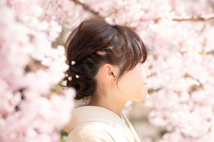 Close-up of young woman with pink cherry blossom