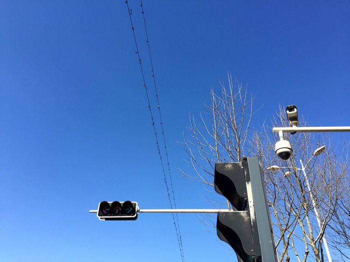 Low angle view of cctv camera and road signal against clear sky