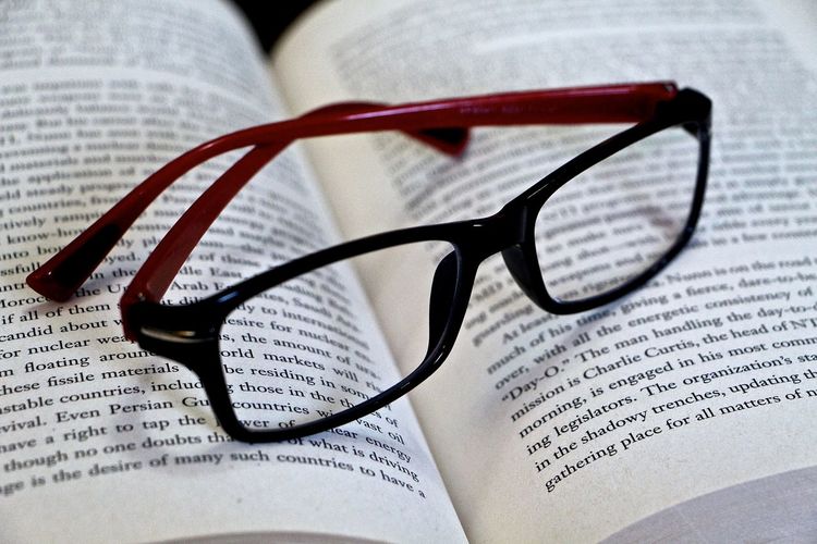 Close-up of eyeglass on open book