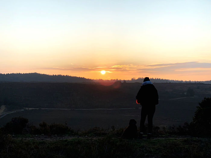 Rear view of silhouette man standing against sky during sunset