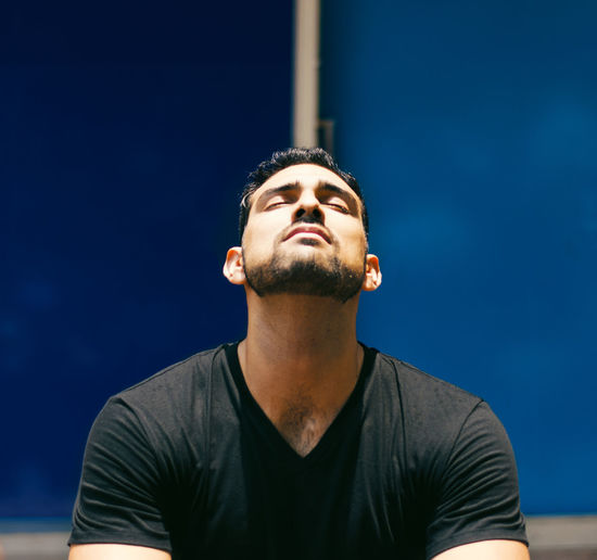 Low angle view of man looking away against blue sky