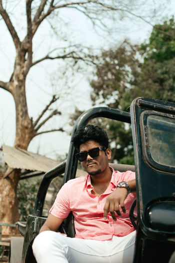 Man riding sunglasses sitting on car