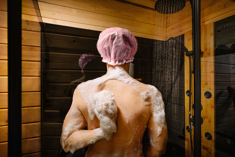 Man taking shower in wooden bathroom