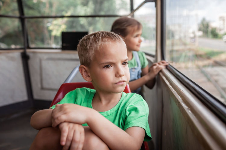 Kids ride in empty tram and look at the window attentively, public transportation, city tramway