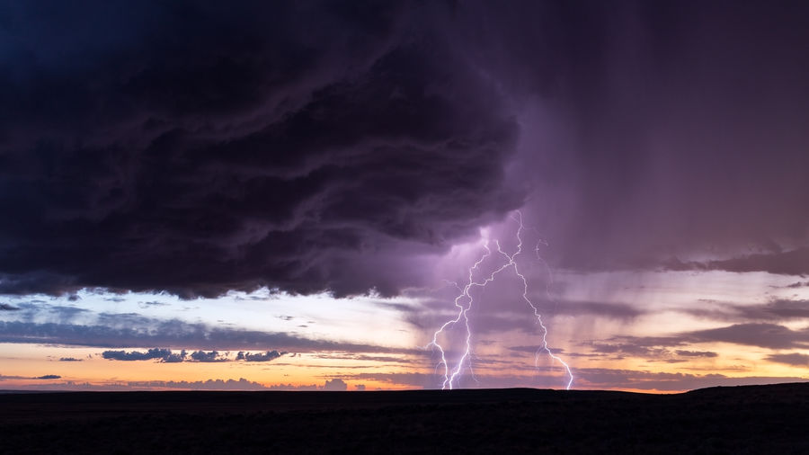 Panoramic view of lightning over landscape against storm clouds