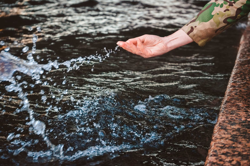 The girl's hand splashes water and drops fly. touching the river with the palm of your hand 