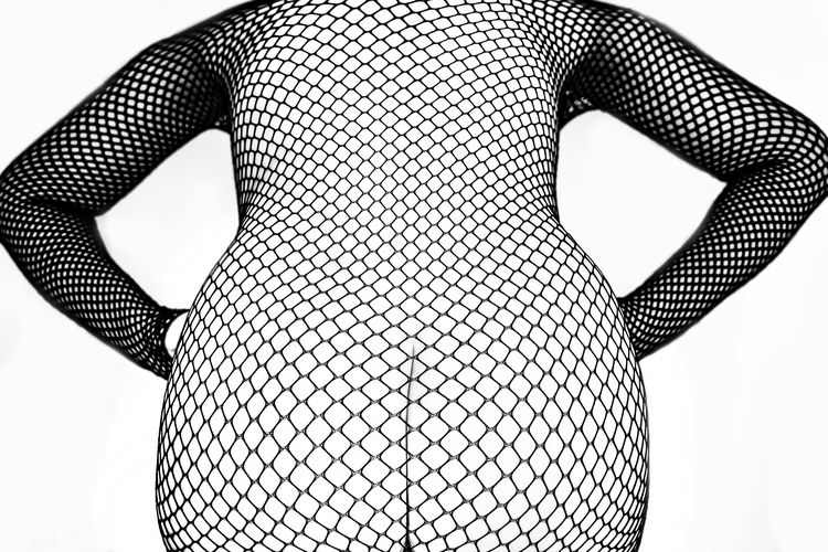 Midsection of seductive woman in netting against white background