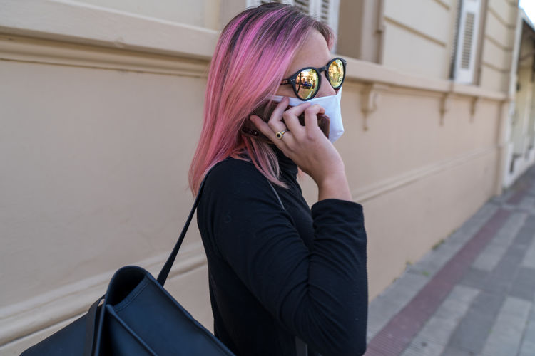 Woman wearing face mask using phone
attractive woman walking through street wearing protective masa