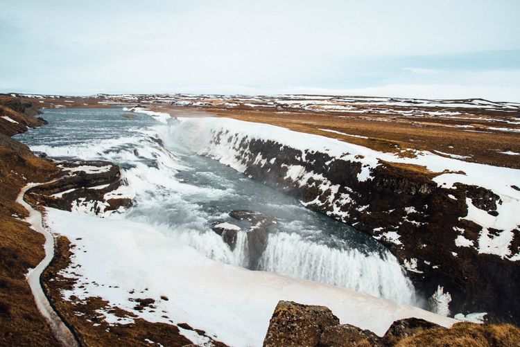 Scenic view of gullfoss falls against sky during winter