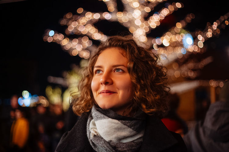 Curly young woman in night festive lights