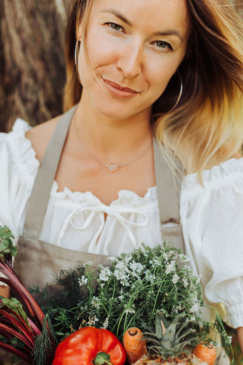 Close up portrait of a female farmer with herbs looking at camera