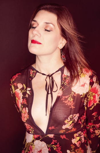Portrait of young woman standing against black background