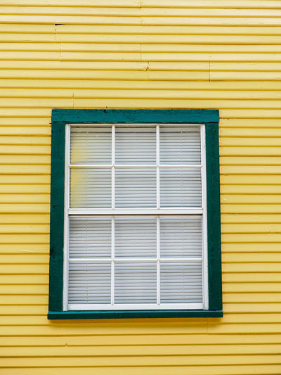 Green framed window on a yellow building
