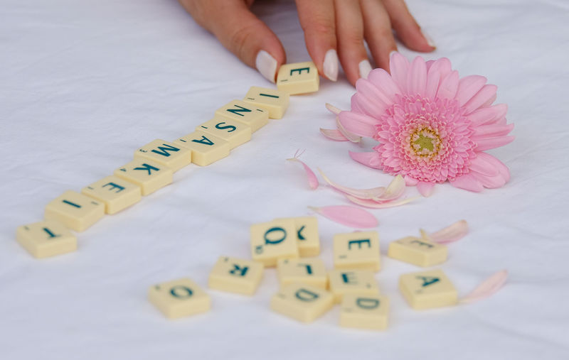 Cropped hands of woman adjusting letters by flower on table